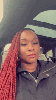 a woman with red braids is sitting in a car .