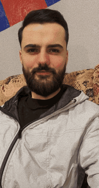 a man with a beard wearing a grey jacket