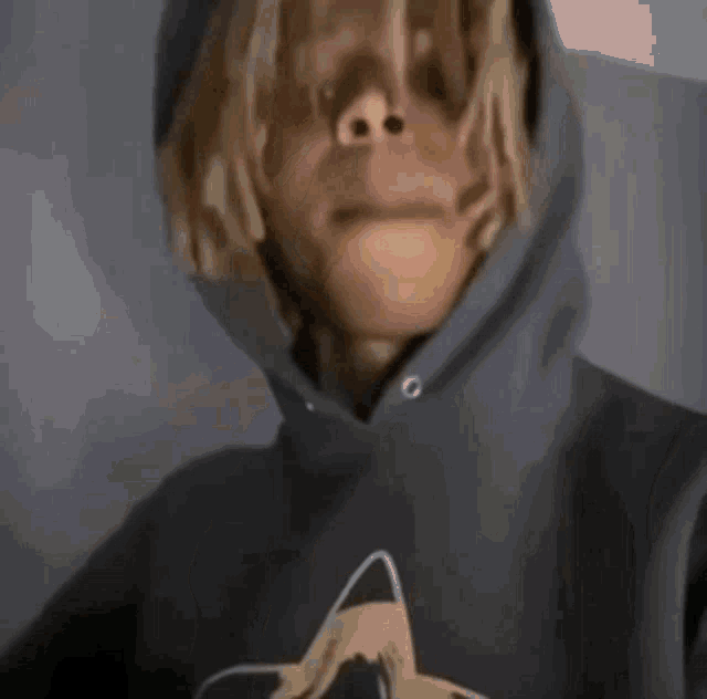 a man with dreadlocks is wearing a hoodie and making a face .