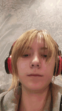 a woman wearing headphones looks at the camera