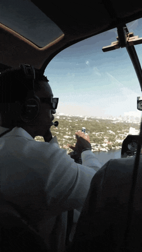 a man wearing bose headphones looks out the window of an airplane