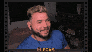 a man wearing ear buds and a blue shirt with the word eliges on the bottom right