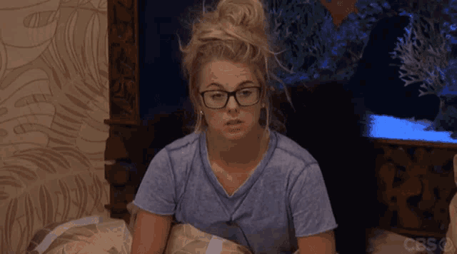 a woman wearing glasses is sitting on a bed