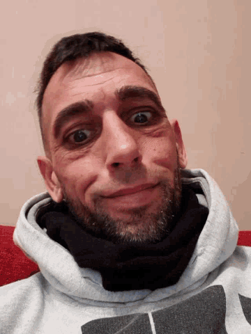 a man with a beard is wearing a grey hoodie with a black letter a on it