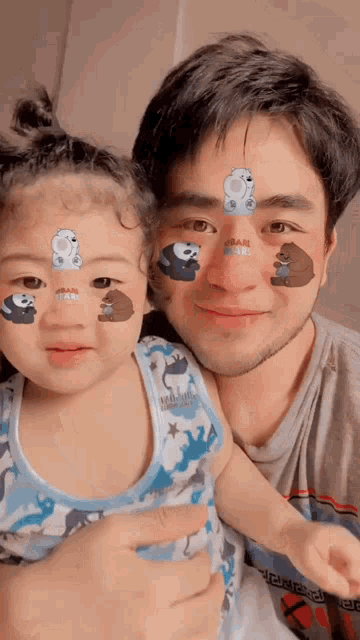 a man is holding a little girl with we bare bears on her face