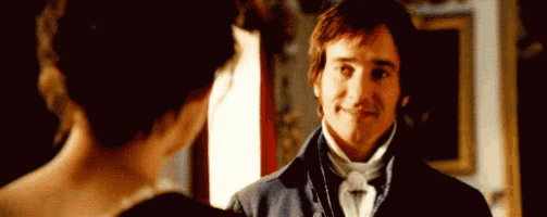a man and a woman are standing next to each other in a room and smiling at each other .