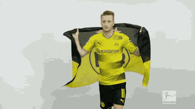 a man in a yellow and black evonik jersey is holding a black and yellow flag