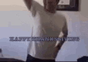 a man in a white shirt is dancing in a room with the words `` happy thanksgiving '' written in the background .