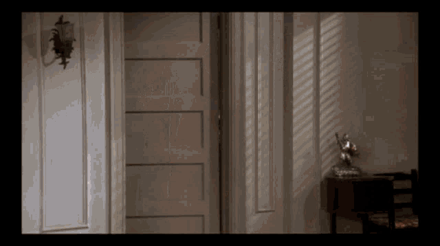 a room with a lamp on the wall and a door open