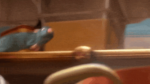 a cartoon rat is sitting on a wooden spoon in a kitchen .