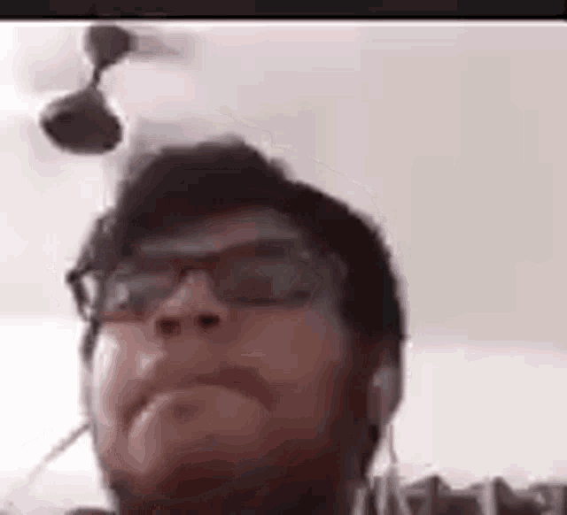 a man wearing glasses and ear buds is looking at the camera on a video call .