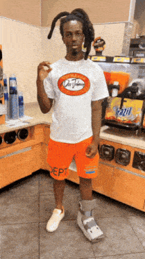 a man wearing orange shorts and a white t-shirt with the word vans on it