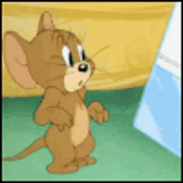 jerry from the cartoon tom and jerry is standing on a green floor looking at something .