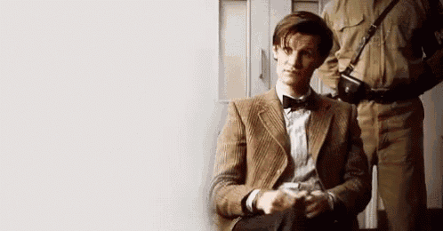 a man in a suit and bow tie is sitting in a chair in front of a door .