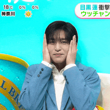 a man in a blue jacket holds his hands to his face in front of a can of beer
