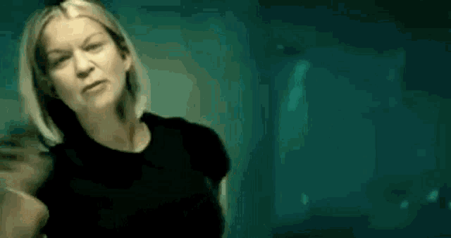 a woman in a black shirt is standing in front of a green background .