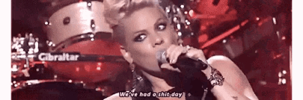 a woman is singing into a microphone and says we 've had a shit day