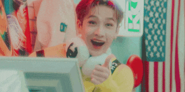 a young man is smiling and giving a thumbs up while holding a stuffed panda .