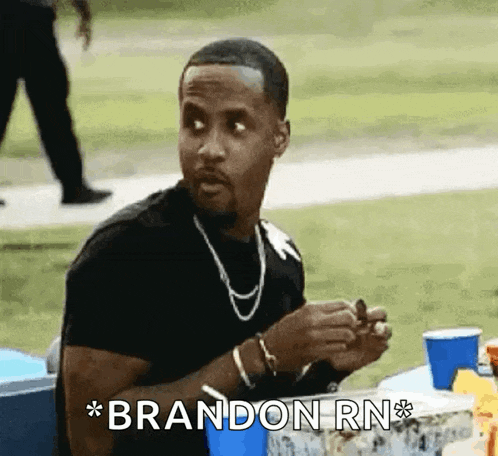 a man is sitting at a table with the words brandon rn written on it .