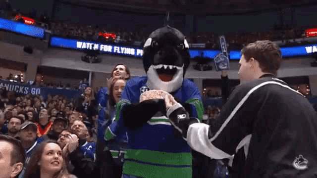 a mascot with the number 50 on his jersey is holding a cake