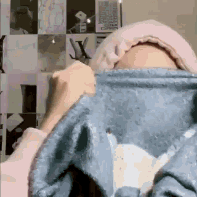 a woman is covering her face with a blanket while wearing a pink hat .
