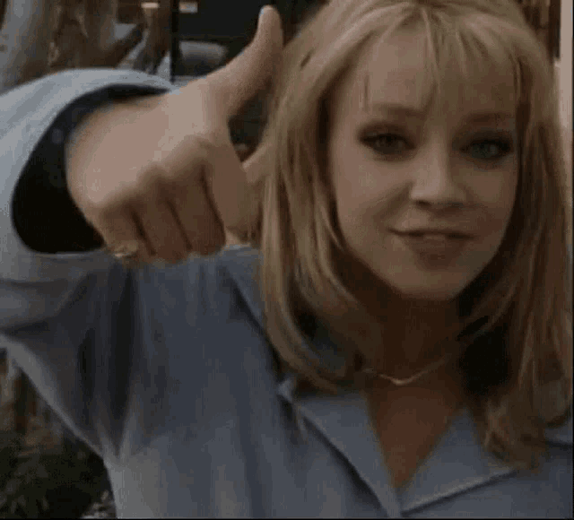 a woman is giving a thumbs up sign and smiling .