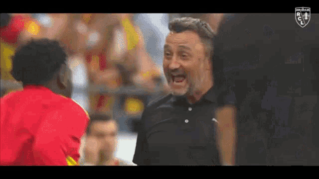 a man with a beard is yelling at a young man in a red shirt .