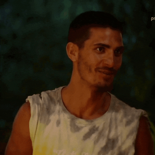 a man in a tie dye shirt is smiling and looking at the camera