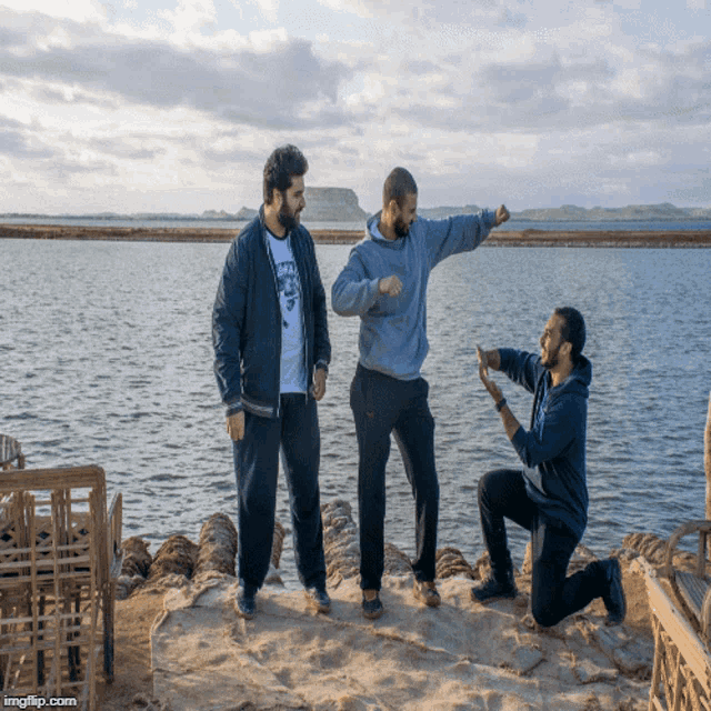 a man wearing a hoodie that says ' the north face ' on it stands between two other men