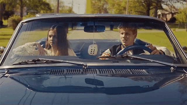 a man is driving a car with a woman sitting in the back