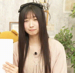 a woman with long black hair is holding a piece of paper and making a funny face .