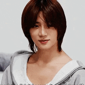 a woman with short brown hair is wearing a white shirt and a grey hoodie .
