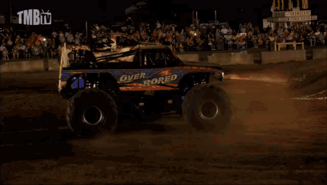 a monster truck is driving on a dirt track with tmb tv written on the bottom