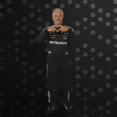 a man wearing a petronas outfit makes a heart shape with his hands