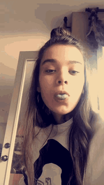 a girl taking a selfie in front of a door with her mouth open