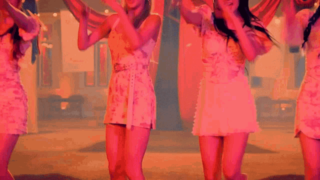 a group of girls in pink dresses are dancing on a stage