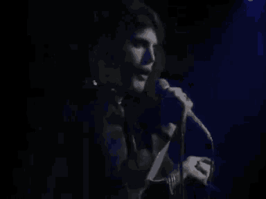 a man is singing into a microphone in the dark .