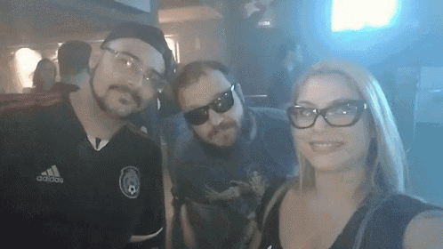 three people posing for a picture with one wearing a shirt that says adidas