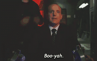 a man in a suit says boo-yah in a dark room