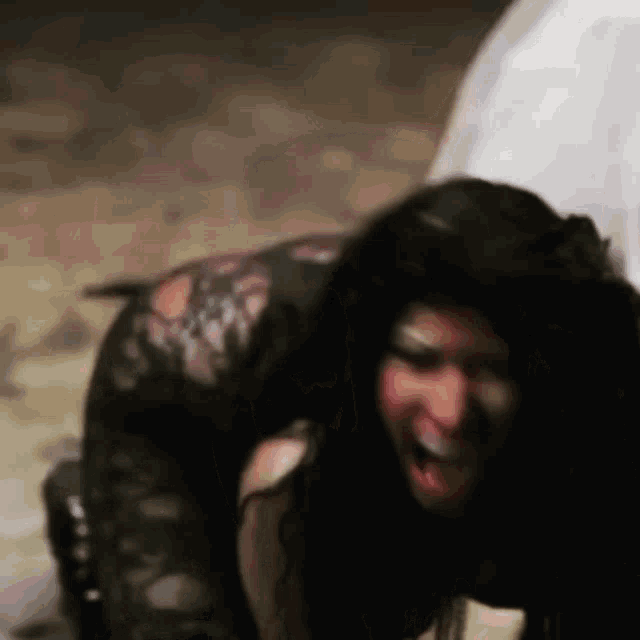 a woman in a black dress is kneeling down on the floor with her tongue out .
