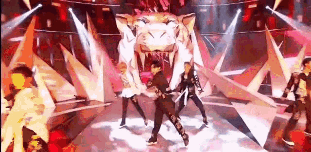 a group of people are dancing on a stage in front of a tiger head .