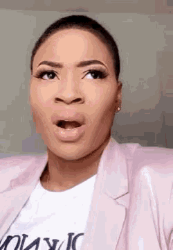 a woman wearing a pink jacket and a white shirt is making a funny face .