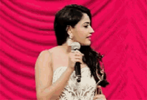 a woman in a white dress is holding a microphone and talking to a man