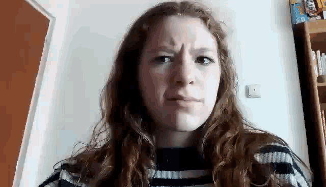 a young woman with long red hair is making a funny face .