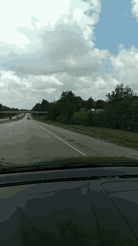a car is driving down a highway with a bridge in the background