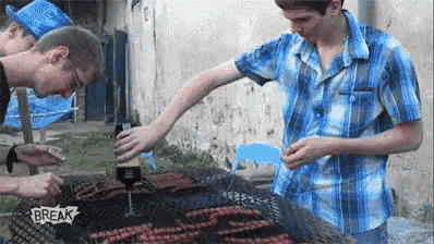 a group of young men are cooking sausages on a grill with a sign that says break on it .
