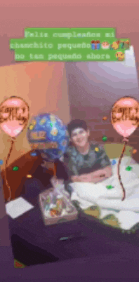 a person is sitting in a bed with balloons that say happy birthday on them