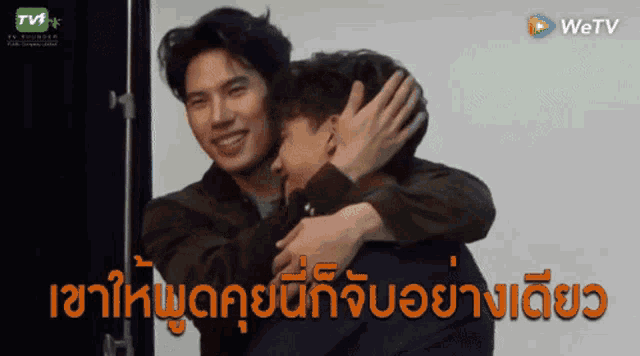 two men hugging each other in front of a tv screen