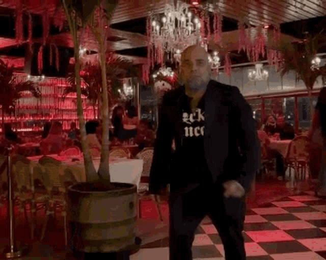 a man wearing a black shirt that says rick nec is dancing in a restaurant .