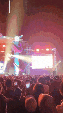 a crowd of people watching a concert with a large screen behind them that says ' a '